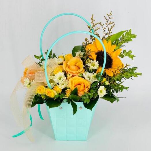 A bouquet of yellow roses with a sunflower in a handbag