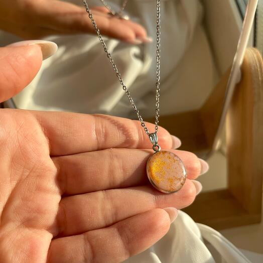 Pink pendant in the shape of a circle with golden pollen