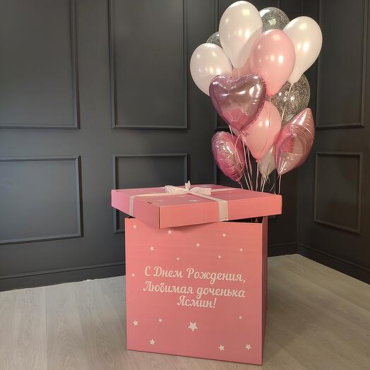 Un arreglo de bolas blancas y Rosadas y transparentes con lentejuelas plateadas, corazones y estrellas en una Caja rosa