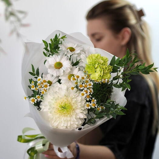 Элегантный букет из белых хризантем, ромашек и зелени, перевязанный зелёной лентой