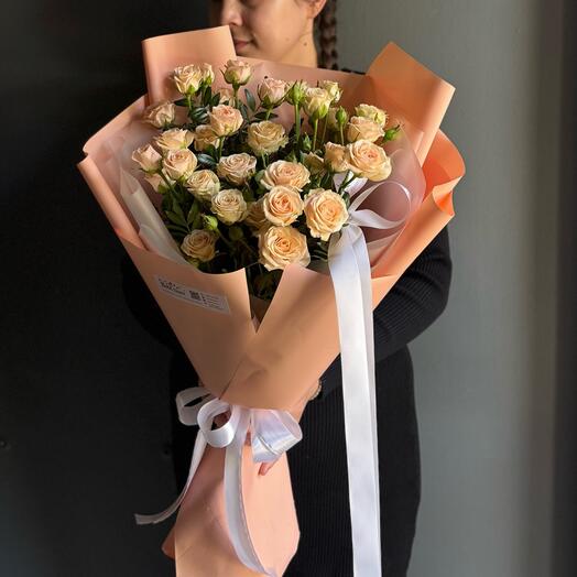 Букет из кремовых кустовых роз в нежной воздушной упаковке с добавлением пышного банта из атласных лент