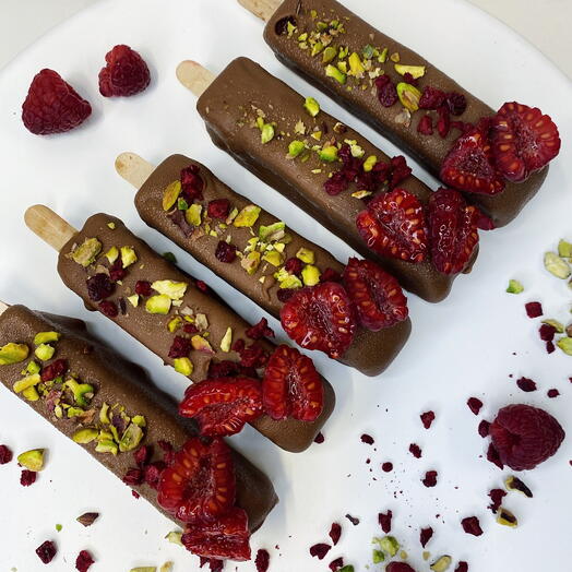 Pistachio cheesecakes on sticks with strawberry filling in milk chocolate