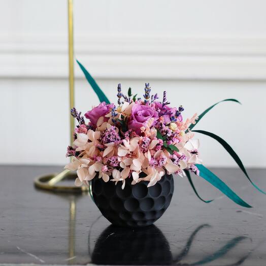 A composition of stabilized flowers and dried flowers in a Violet planter