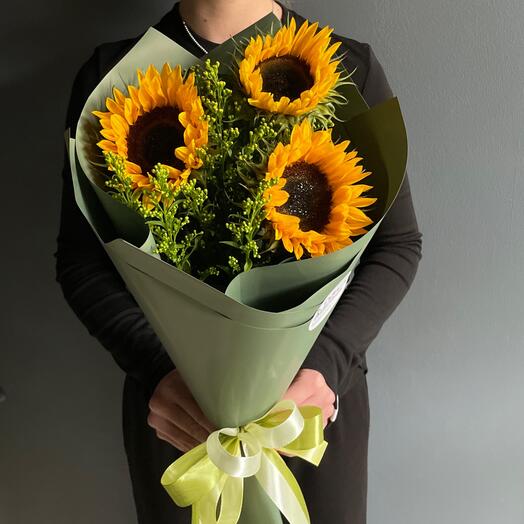 Букет из ярких подсолнухов с добавлением зелени в декоративной упаковке с бабочками
