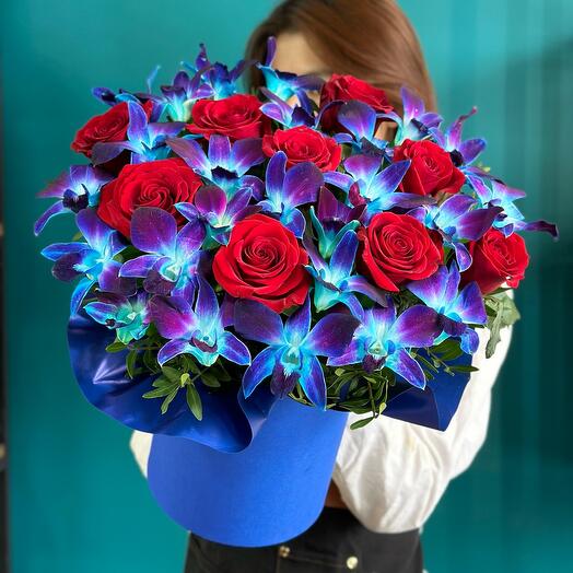 Bright and stylish arrangement of red roses and blue orchids in a box