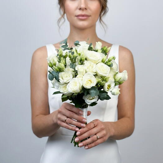 Delicate white bridal bouquet of bush roses, lisianthus and eucalyptus