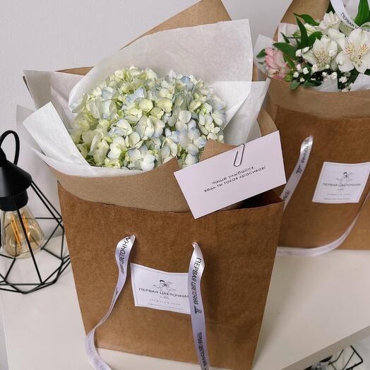 A bouquet of hydrangeas in a branded handbag