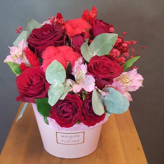 The flowers are red in a pink box. Red rose with cotton