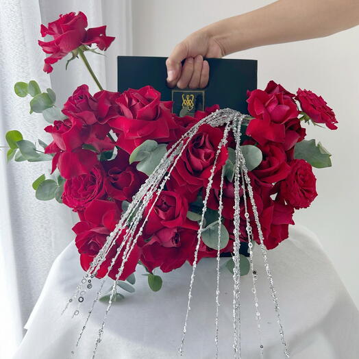 Red roses in a handle box with shinning accessories