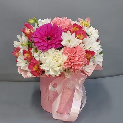 A bright bouquet of roses and chrysanthemums in a hatbox