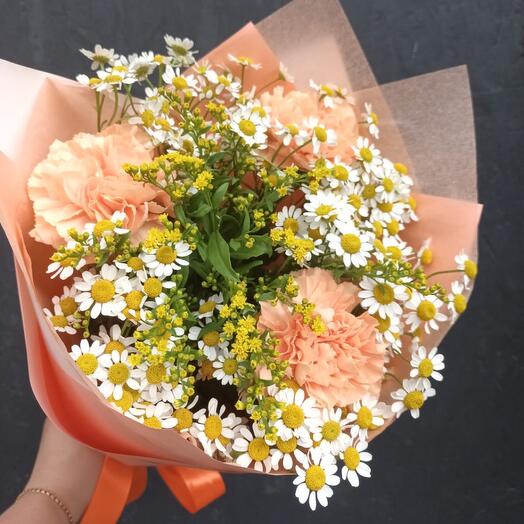 A bouquet of daisies with delicate peach cloves and decorative greenery in a stylish package
