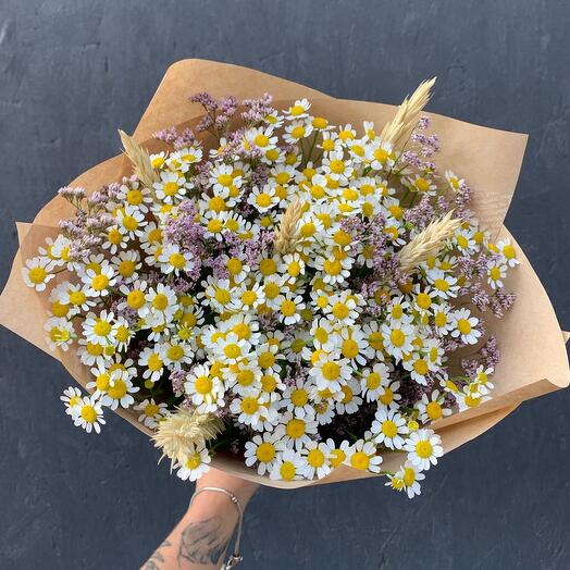 A bouquet of daisies with limonium and trinicum in a stylish package