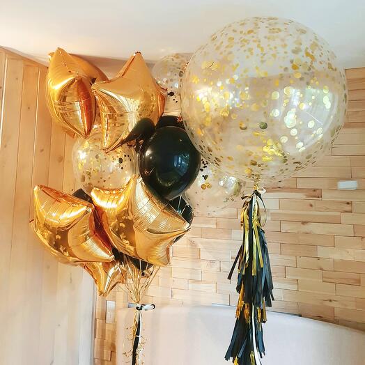 A bouquet of giant balloons with confetti and a golden fountain