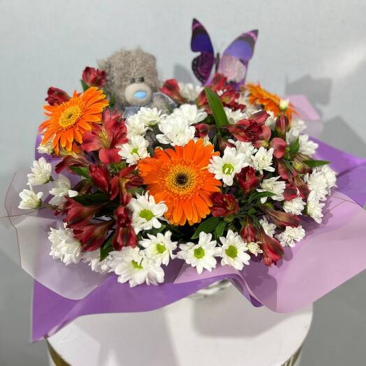 A bouquet of flowers with a stuffed toy in a basket