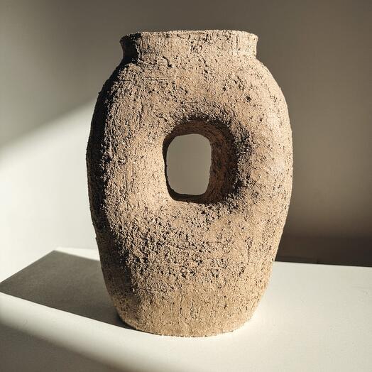 A vase with a hole in the style primal
