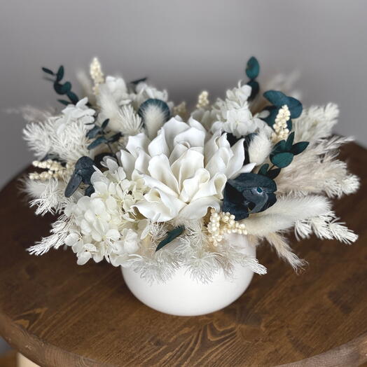 A composition of dried flowers and stabilized flowers in a ceramic planter, a white-green range for the interior