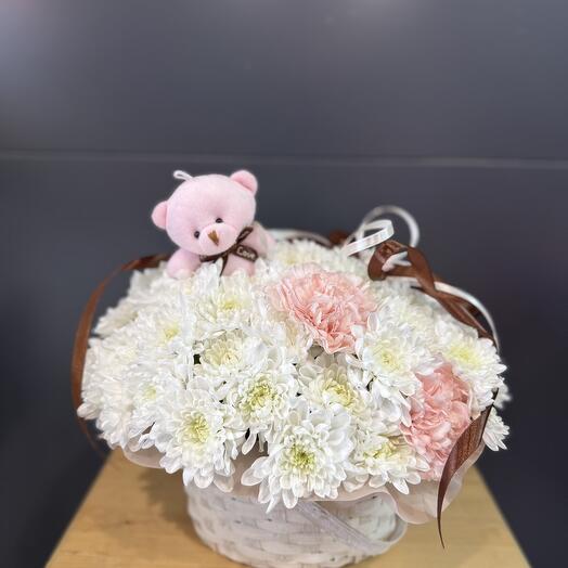 A basket with flowers and a pink teddy bear