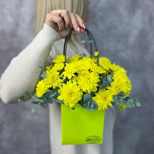 A bright composition of bush chrysanthemum with fragrant eucalyptus in a fashionable handbag