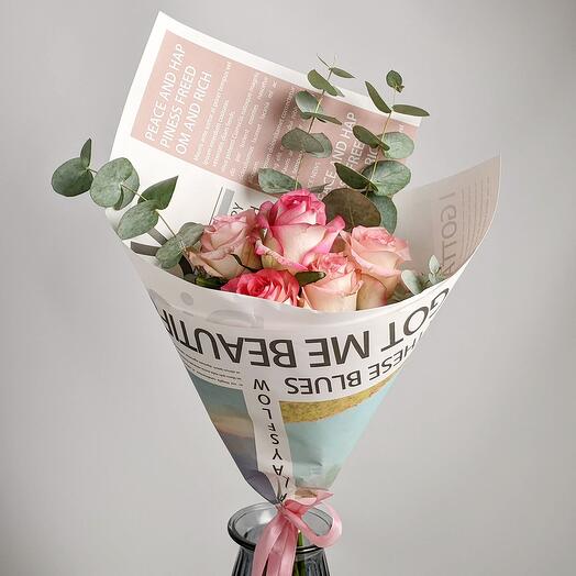 Five pink roses in a newspaper wrap with eucalyptus