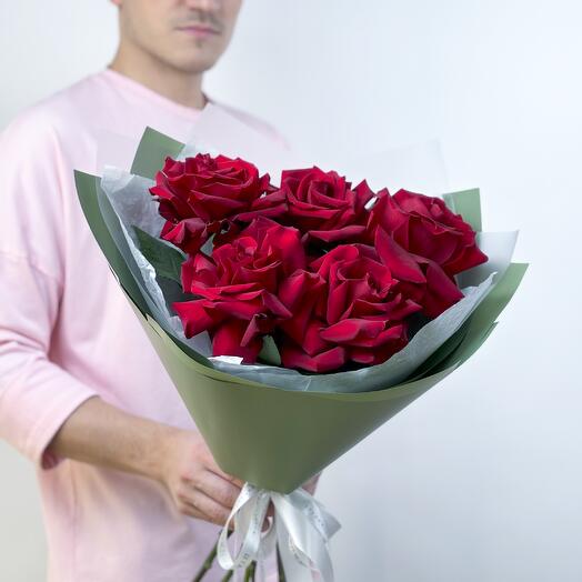 A bright bouquet of red French roses in a green package