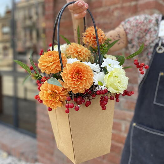 Composition with orange dahlias in a craft bag