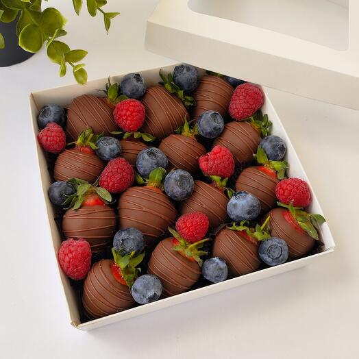 Strawberries in milk chocolate with raspberries and blueberries